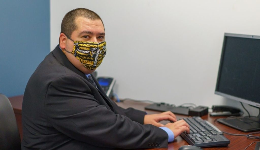 Masked IntelliDyne employee working in front of a computer