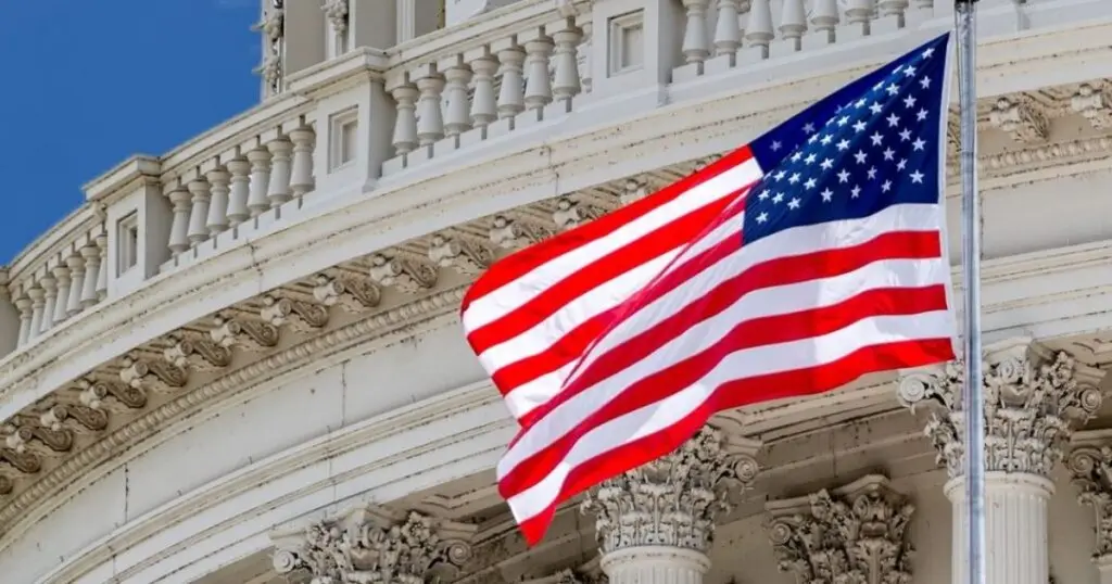 Image of the American flag waving in the wind in front of a federal government building